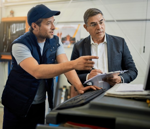 Auto repairman and manager cooperating while using computer in a